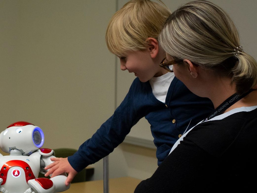 Child reaching out to touch a robot